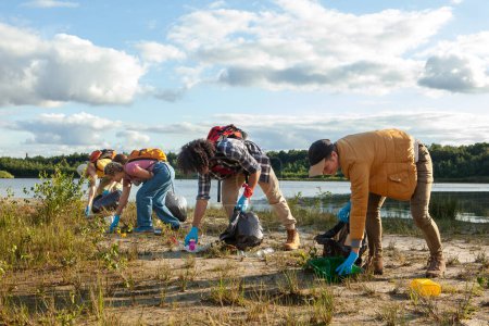 A diligent team works together to clean a lakes shore, contributing to environmental conservation. Group Effort in Lakeside Cleanup by Eco-Conscious Volunteers. High quality photo