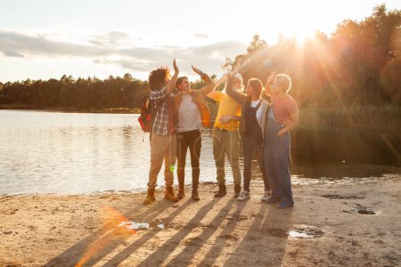 Cinco amigos comparten un momento de conexión en la puesta de sol brillante en una orilla del lago. Grupo de amigos disfrutando de una hermosa puesta de sol junto al lago. Foto de alta calidad