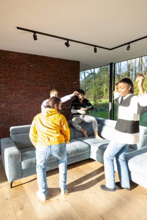 This lively scene captures a group of friends dancing and enjoying themselves in a bright and spacious living room. The setting is modern and inviting, with large windows offering views of the