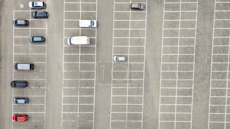 Téléchargez les photos : Une photographie aérienne capture un grand parking vide avec seulement quelques voitures éparpillées à travers les espaces soigneusement marqués. L'image présente différents types de véhicules, y compris les berlines et les VUS, avec - en image libre de droit