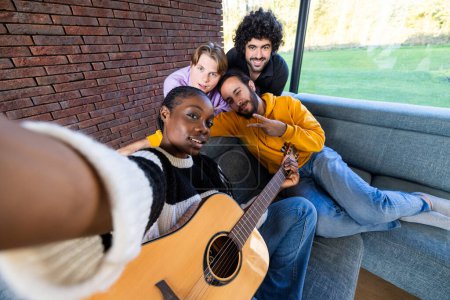 This vibrant image captures a joyful gathering of four diverse friends in a modern living room. A Black woman, holding a guitar, takes a selfie with her friends, a White woman, a Middle Eastern man