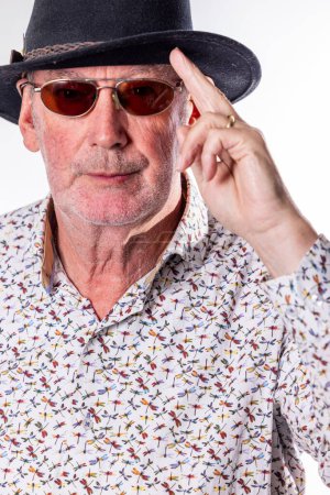 A man sporting a fedora and sunglasses is gesturing towards his forehead, highlighting the importance of vision care and wearing protective eyewear