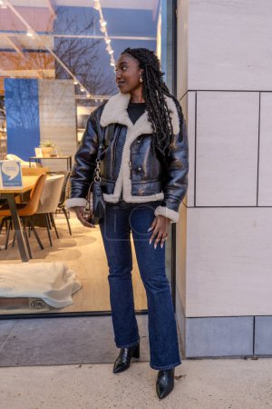 Trendy woman wearing a leather jacket poses outside a chic caf during fall