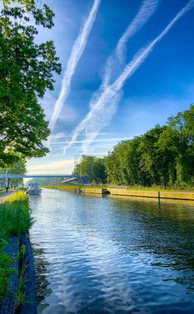Ein ruhiger Fluss mit Booten, grünen Bäumen und blauem Himmel, der sich im ruhigen Wasser spiegelt, ist ein friedlicher Anblick in der Natur