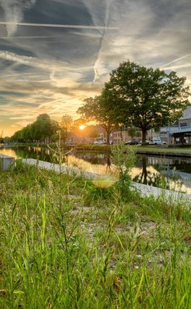 Das Dorf am Fluss ist in wunderschönes Sonnenuntergangslicht getaucht, umgeben von üppigem Grün und friedlichem Wasser
