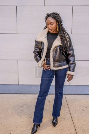 Stilvolle Frau im Winteroutfit schwarze Kunstpelzjacke, Jeans, Stiefeletten für trendigen Straßenstil