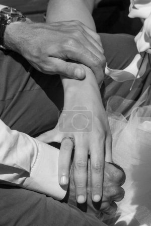 Close-up image of a couple holding hands, depicting love and connection, in a black and white filter.