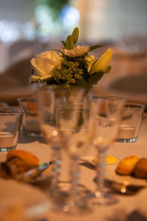 Gros plan d'une table de réception de mariage magnifiquement arrangée avec des verres en cristal et une pièce maîtresse florale.