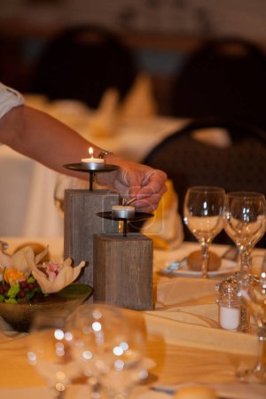 Une table magnifiquement aménagée avec des bougies allumées, des verres à vin et une pièce maîtresse florale créant une ambiance intime.