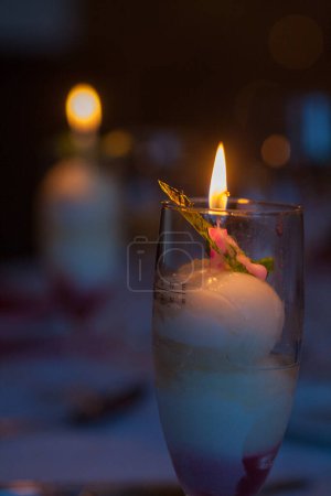 Imagine una vela brillante posicionada sobre vidrio, creando un ambiente acogedor e íntimo con su luz cálida y romántica