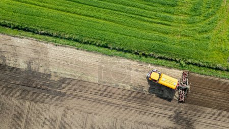 A drone captures aerial footage of farmland with modern tractor equipment working on crops, showcasing agriculture