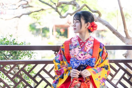 Eine junge Japanerin in ihren 20ern trägt Ryuso in einem chinesischen Garten in Naha City, Präfektur Okinawa