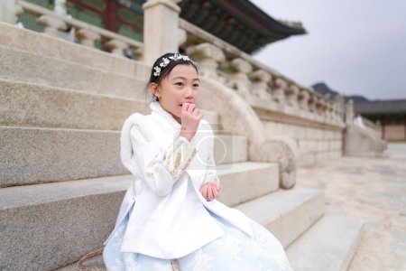 Ein koreanisches Mädchen lacht in einem weißen Hanbok, einer traditionellen Tracht, im Gyeongbokgung Palace in Seoul, Südkorea, in die Kamera