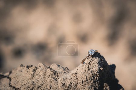 Photo for Abandoned diamond engagement ring resting on top of a rock in summer sunshine - Royalty Free Image