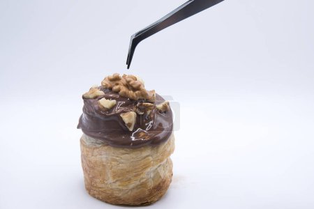 Téléchargez les photos : New yok roll con glaseado de chocolate con leche y nuez, con pinzas - en image libre de droit