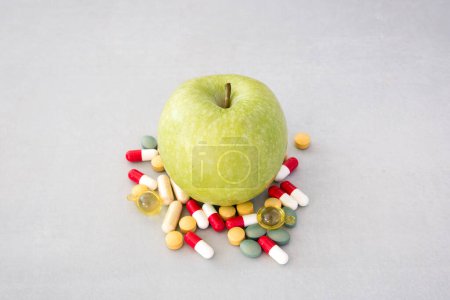 Téléchargez les photos : Pomme verte avec une pile de médicaments à côté - en image libre de droit