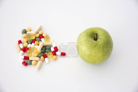 Téléchargez les photos : Pomme verte avec une pile de médicaments à côté - en image libre de droit