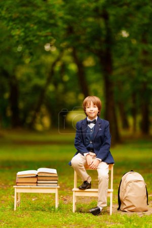 Téléchargez les photos : Joli écolier avec livres et sac à dos dans le parc, enfant étudiant à l'extérieur. Le 1er septembre. Dernière cloche de l'école. Retour à l'école.Photo de haute qualité. Fond flou. - en image libre de droit