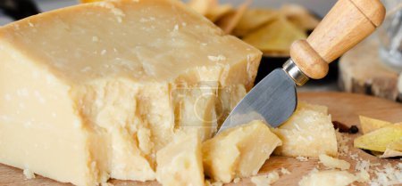 Parmesan cheese cut with knife. Italian food background. Close up