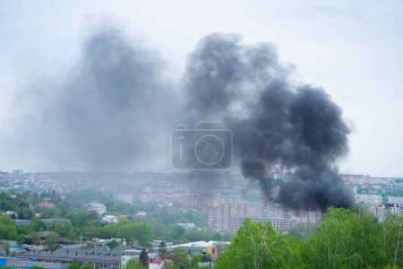 Téléchargez les photos : De la fumée noire s'élève sur les bâtiments et les arbres en vue panoramique. Concept d'urgence. - en image libre de droit