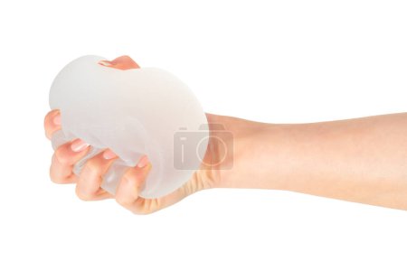 Téléchargez les photos : Main féminine serrant l'implant mammaire rond doux sur fond blanc. Chirurgie plastique. - en image libre de droit