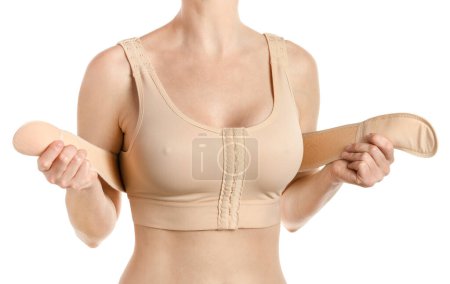 Téléchargez les photos : Femme portant un soutien-gorge de compression avec un stipe après l'augmentation mammaire. Isolé sur fond blanc avec chemin de coupe. - en image libre de droit