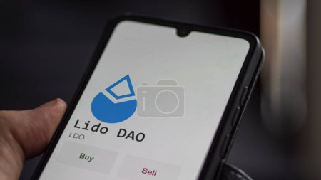 Téléchargez les photos : Un investisseur analyse la pièce Lido DAO à l'écran. Un téléphone montre les prix de l'ETF pour investir dans LDO - en image libre de droit