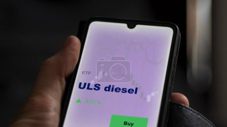 Photo for An investor analyzing the uls diesel etf fund on a screen. A phone shows the prices of ULS diesel - Royalty Free Image