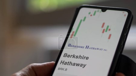 Foto de El logo de Berkshire Hathaway en la pantalla de un intercambio. acciones de precios de Berkshire Hathaway, $BRK.B en un dispositivo. - Imagen libre de derechos