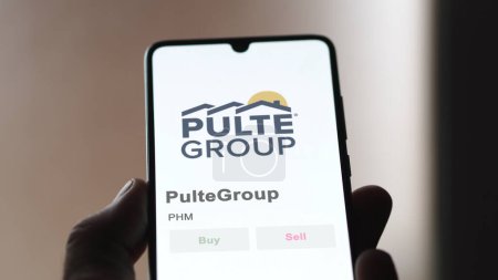 Foto de The logo of PulteGroup on the screen of an exchange. Pulte Group price stocks, $PHM on a device. - Imagen libre de derechos