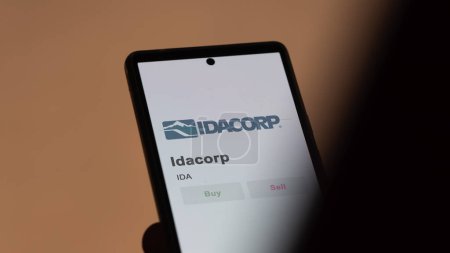 Téléchargez les photos : La page de trading d'Idacorp sur une bourse, un actionnaire analysant $IDA, Idacorp, sur un appareil. - en image libre de droit