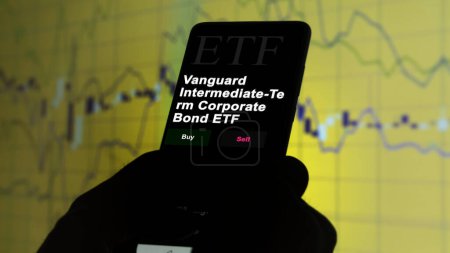 Photo for November 17th 2023. An investor analyzing on a phone an etf fund Vanguard Intermediate-Term Corporate Bond ETF. - Royalty Free Image