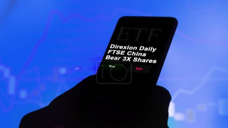 Téléchargez les photos : 17 novembre 2023. Un investisseur analyse par téléphone un fonds etf Direxion Daily FTSE China Bear 3X Actions. - en image libre de droit