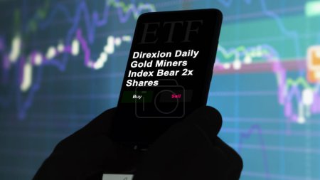 Téléchargez les photos : 17 novembre 2023. Un investisseur analyse par téléphone un fonds etf Direxion Daily Gold Miners Index Bear 2x Shares. - en image libre de droit