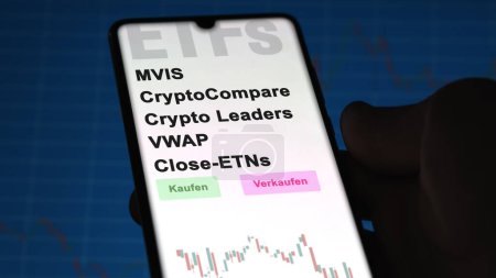 Photo for December 2022. An investor analyzes the MVIS CryptoCompare Crypto Leaders VWAP Close ETNs ETF fund on phone screen MVIS CryptoCompare Crypto Leaders VWAP Close-ETNs. German text translated: Kaufen, Verkaufen, MVIS CryptoCompare Crypto Leaders VWAP Cl - Royalty Free Image
