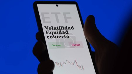 Photo for An investor analyzing an etf fund. ETF text in Spanish : volatility hedged equity, buy, sell. - Royalty Free Image