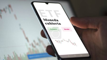 Photo for An investor analyzing an etf fund. ETF text in Spanish : currency hedged, buy, sell. - Royalty Free Image