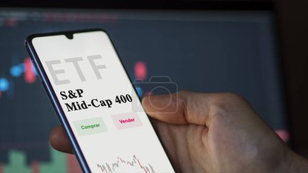Photo for March 2023, An investor analyzing an etf fund. ETF text in Spanish : SandP mid-cap 400, buy, sell. - Royalty Free Image