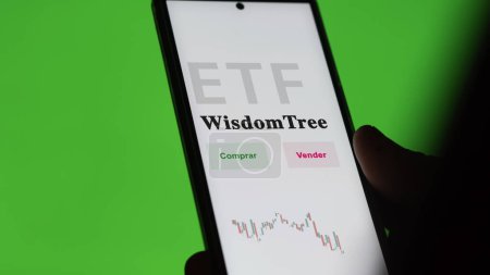 Téléchargez les photos : Un investisseur analysant un fonds etf. Texte de l'ETF en espagnol : WisdomTree, buy, sell. - en image libre de droit