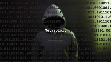 Cyber attack metasploit text in foreground screen, anonymous hacker hidden with hoodie in the blurred background. Vulnerability text in binary system code on editor program.