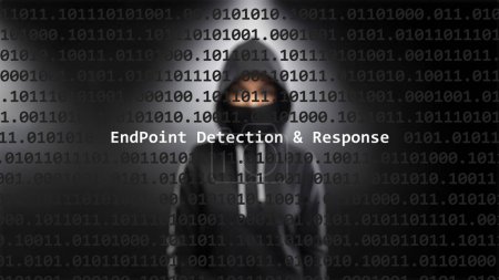 Cyberattaque Endpoint détection & texte de réponse dans l'écran de premier plan, pirate anonyme caché avec sweat à capuche dans l'arrière-plan flou. Texte de vulnérabilité dans le code système binaire sur le programme d'éditeur.