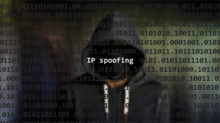 Cyber-Angriff ip Spoofing Text im Vordergrund, anonymer Hacker versteckt mit Kapuzenpulli im verschwommenen Hintergrund. Verwundbarkeitstext im binären Systemcode im Editor-Programm.