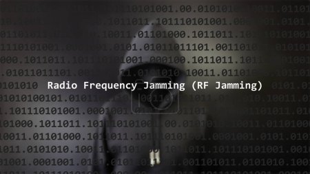 Cyber attack radio frequency jamming (rf jamming) text in foreground screen, anonymous hacker hidden with hoodie in the blurred background. Vulnerability text in binary system code on editor program.