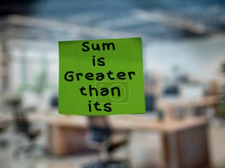 Post note on glass with 'The Sum is Greater than its Parts'.