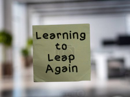 Post note on glass with 'Learning to Leap Again'.