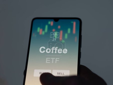 An investor analyzing the coffee etf fund on a screen. A phone shows the prices of Coffee