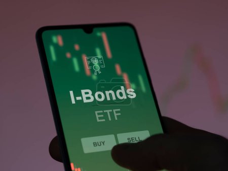 An investor analyzing the i-bonds etf fund on a screen. A phone shows the prices of I-Bonds