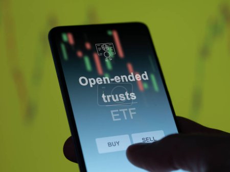 An investor analyzing the open-ended trusts etf fund on a screen. A phone shows the prices of Open-ended trusts