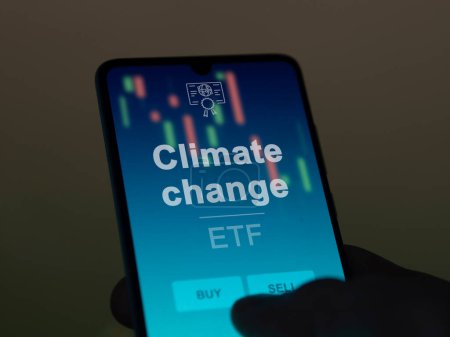 An investor analyzing the climate change etf fund on a screen. A phone shows the prices of Climate change