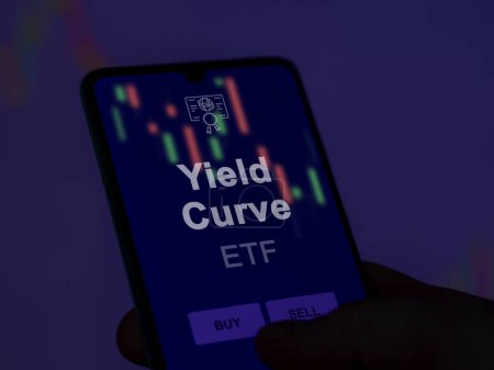 Ein Anleger analysiert die Renditekurve eines Fonds auf einem Bildschirm. Ein Telefon zeigt die Preise der Yield Curve